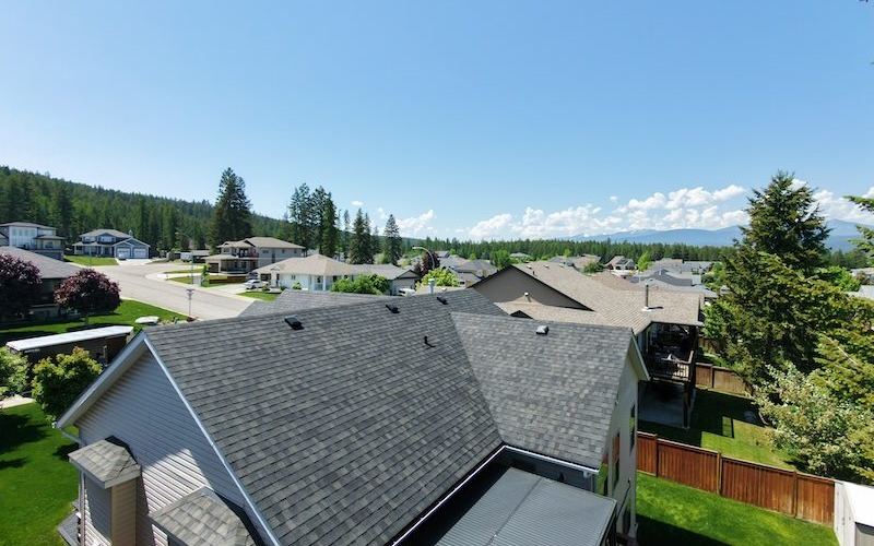 Drone photo of a treated shingle roof with the Rocky Mountains behind