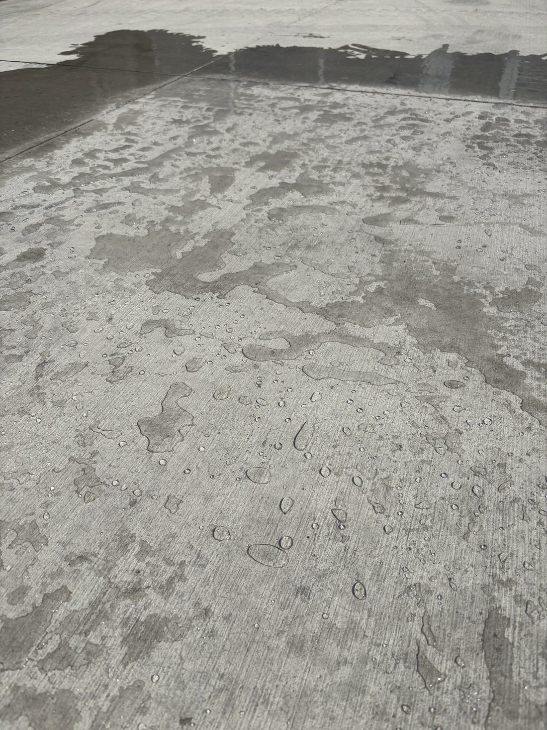 Untreated concrete driveway soaking up water and staying dark and wet